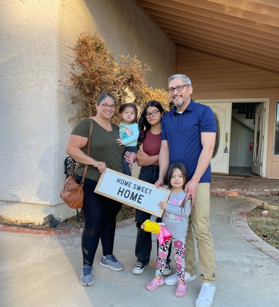 Family of 5 holding a sign that says Home Sweet Home.